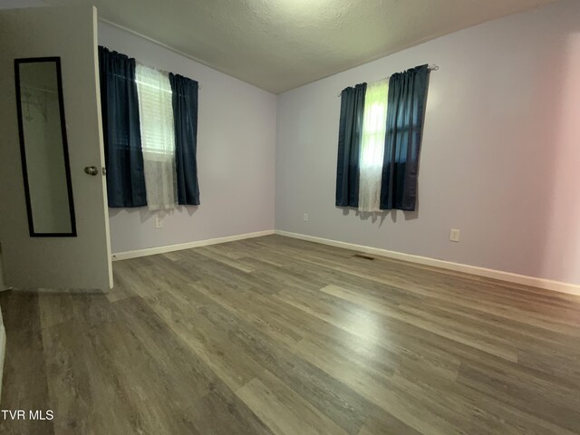unfurnished room with baseboards, wood finished floors, and a textured ceiling