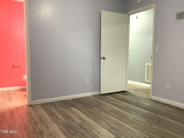 empty room featuring baseboards, visible vents, and wood finished floors