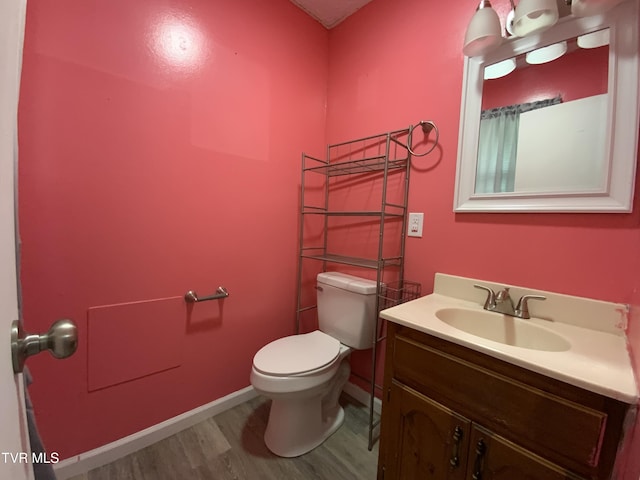 bathroom featuring wood finished floors, toilet, vanity, and baseboards