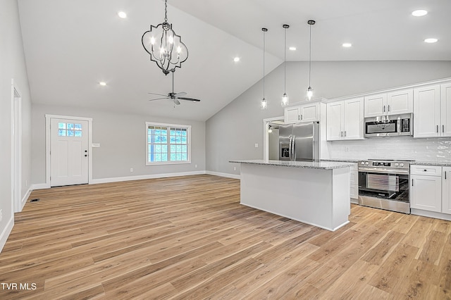 kitchen with decorative backsplash, appliances with stainless steel finishes, white cabinets, a center island, and high vaulted ceiling