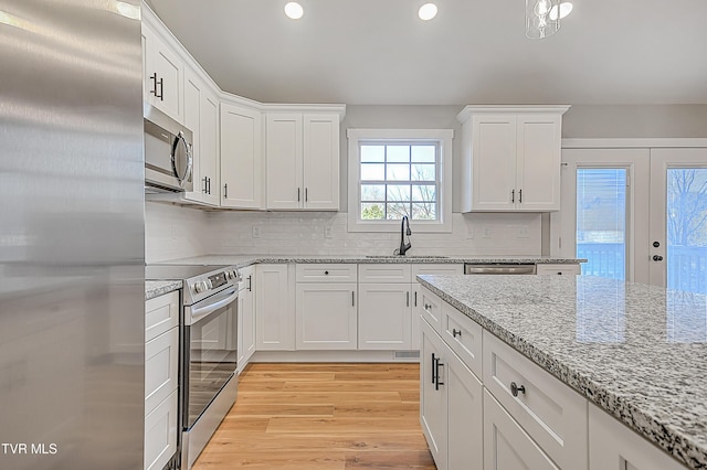kitchen featuring light wood finished floors, recessed lighting, a sink, white cabinets, and appliances with stainless steel finishes