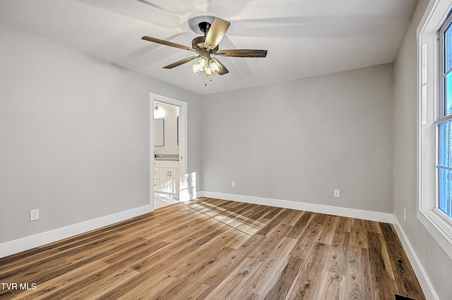 unfurnished room featuring a ceiling fan, wood finished floors, and baseboards