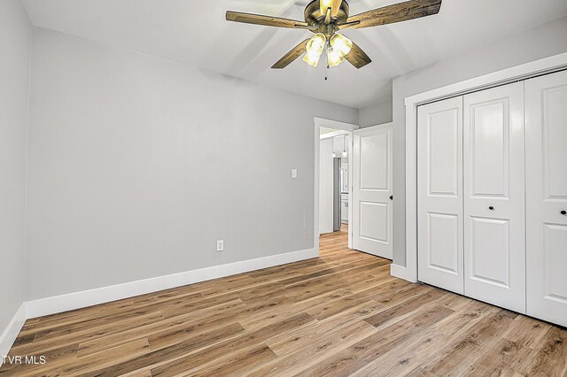 unfurnished bedroom featuring baseboards, ceiling fan, a closet, and light wood finished floors