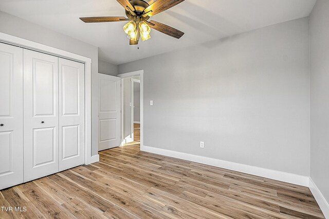 unfurnished bedroom with a closet, a ceiling fan, light wood-style floors, and baseboards