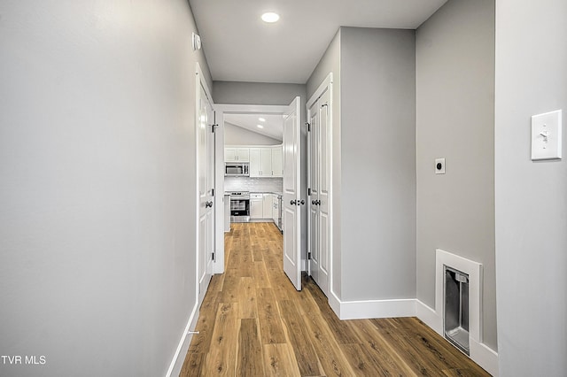hall featuring recessed lighting, baseboards, and light wood-type flooring