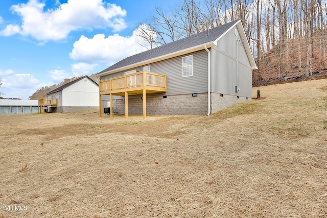 rear view of house with a deck, roof with shingles, and crawl space
