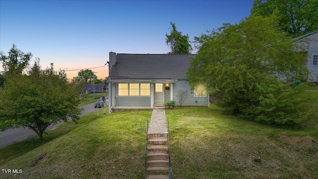 view of front of home featuring roof with shingles and a yard
