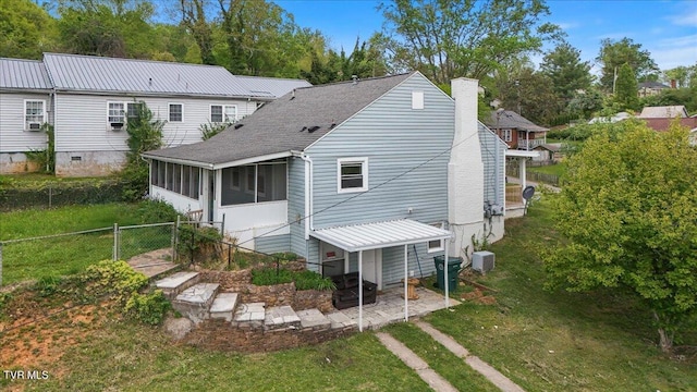 rear view of house featuring a chimney, fence, a sunroom, and a lawn