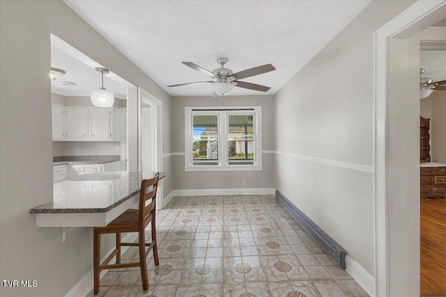 unfurnished dining area with baseboards and ceiling fan