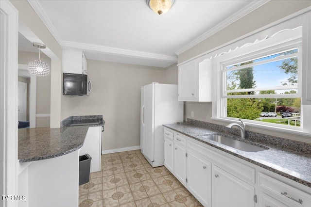 kitchen featuring stainless steel microwave, a sink, white cabinets, and freestanding refrigerator