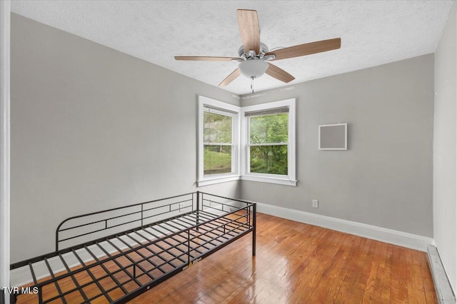 unfurnished bedroom featuring baseboards, a textured ceiling, and wood-type flooring