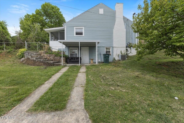 rear view of property with a sunroom, central air condition unit, a yard, driveway, and fence
