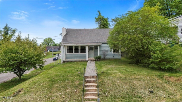 view of front of house with a chimney, a front yard, and roof with shingles