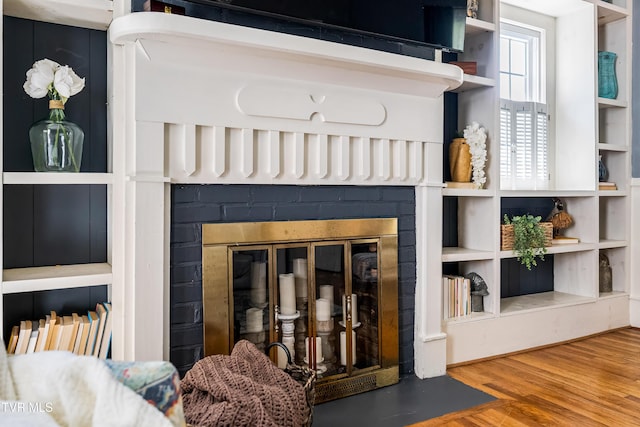 details with a brick fireplace and wood finished floors