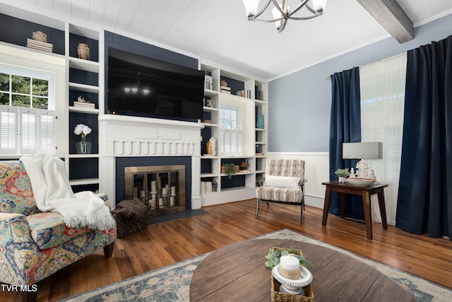 living area with a chandelier, wood finished floors, built in shelves, and a fireplace