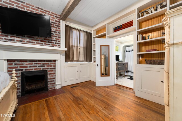 unfurnished living room featuring visible vents, wooden ceiling, beam ceiling, wood-type flooring, and a fireplace