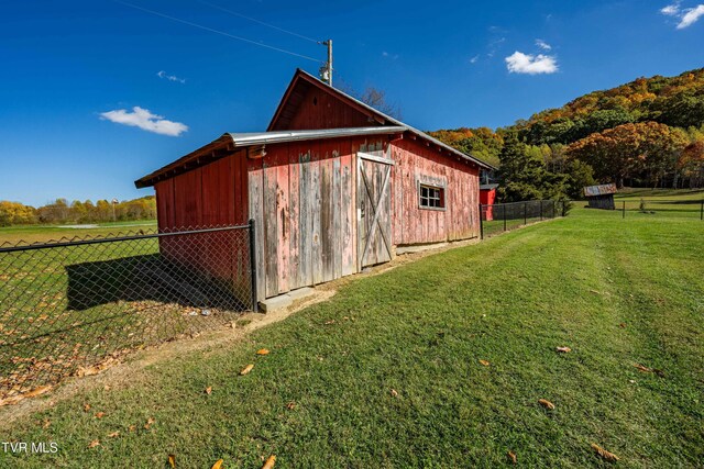 view of outbuilding with fence and an outbuilding