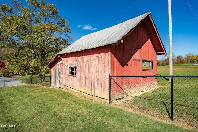 view of barn featuring fence and a lawn