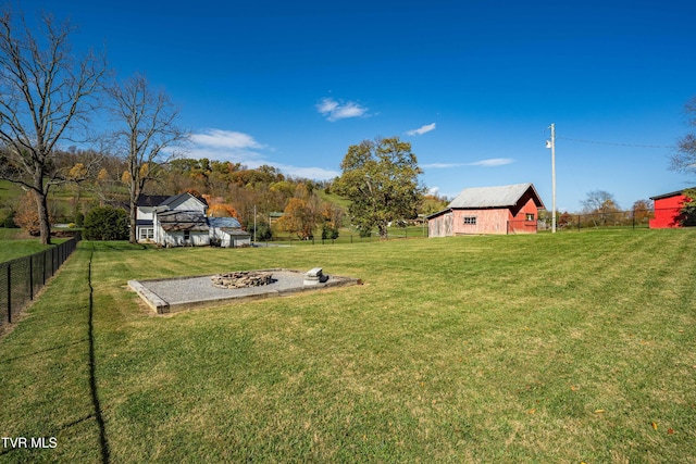 view of yard with fence, an outdoor structure, an outdoor fire pit, and a barn