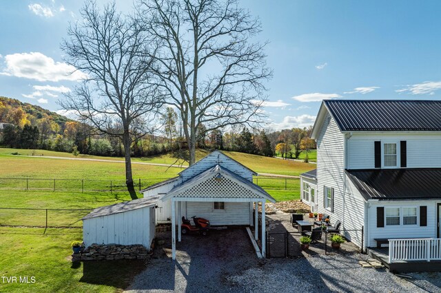 view of side of property featuring fence, a yard, and gravel driveway