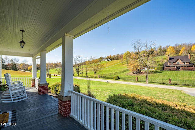 wooden terrace with a lawn and covered porch
