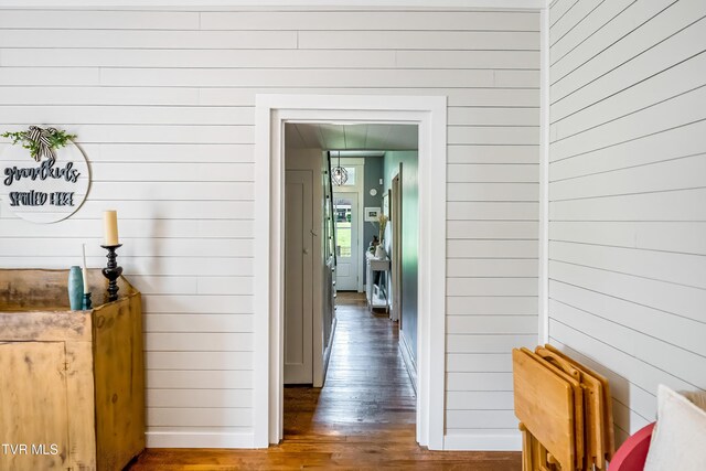 hallway featuring wood walls, hardwood / wood-style flooring, and baseboards