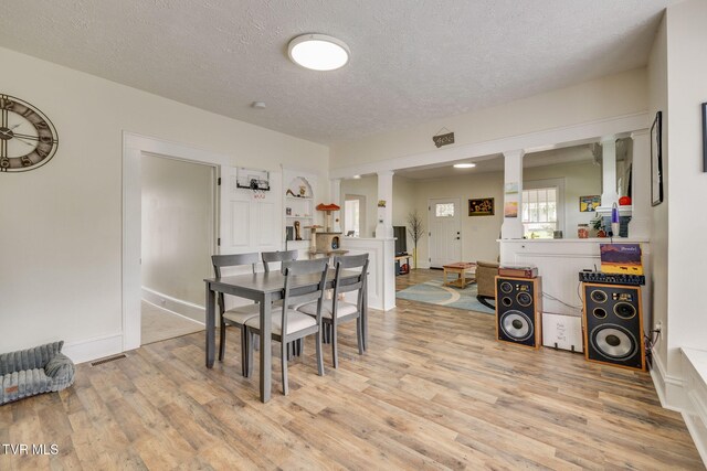 718 Wilson Ave, Johnson City, TN 37604 - dining area featuring ornate columns, light wood-style floors, baseboards, and a textured ceiling