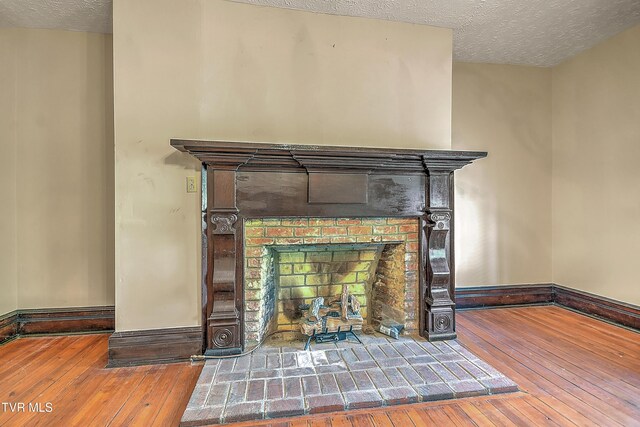 interior details with a textured ceiling, baseboards, wood finished floors, and a fireplace
