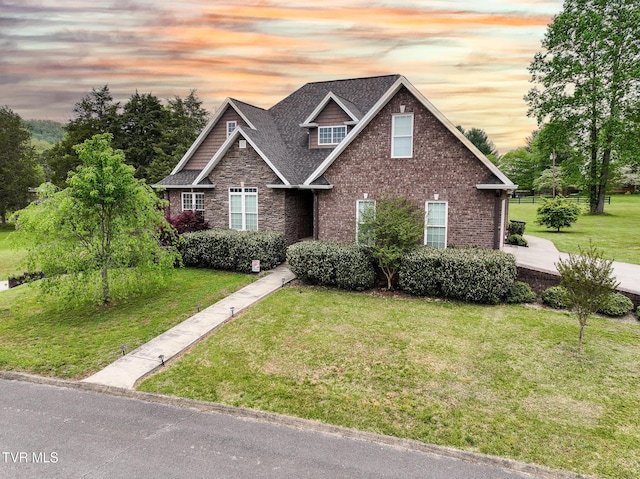 craftsman house with stone siding, brick siding, a shingled roof, and a lawn