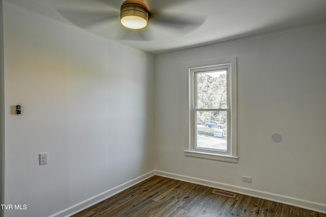 spare room with ceiling fan, visible vents, baseboards, and dark wood-type flooring