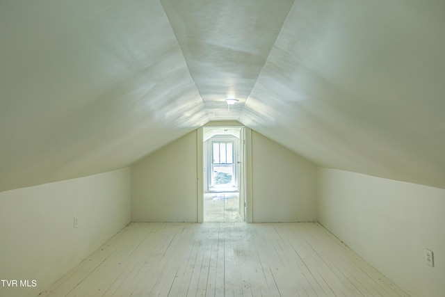 additional living space with wood-type flooring and vaulted ceiling