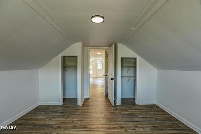 bonus room featuring baseboards, dark wood-style floors, and vaulted ceiling
