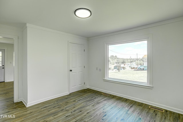unfurnished room featuring visible vents, baseboards, and wood finished floors