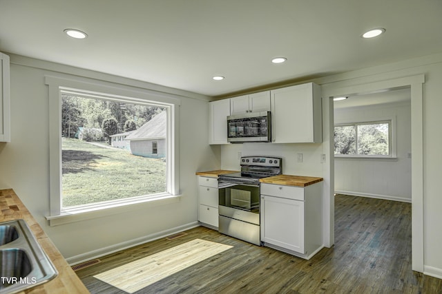 kitchen with white cabinets, appliances with stainless steel finishes, dark wood-style floors, and wooden counters