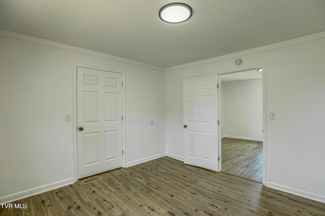 unfurnished bedroom featuring baseboards, visible vents, and wood finished floors