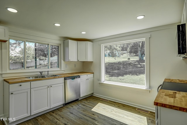 kitchen featuring butcher block countertops, a sink, a wealth of natural light, and stainless steel dishwasher