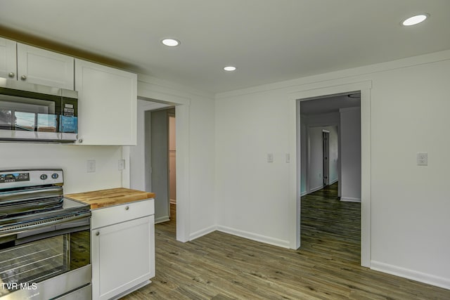 kitchen featuring baseboards, butcher block countertops, white cabinetry, and appliances with stainless steel finishes