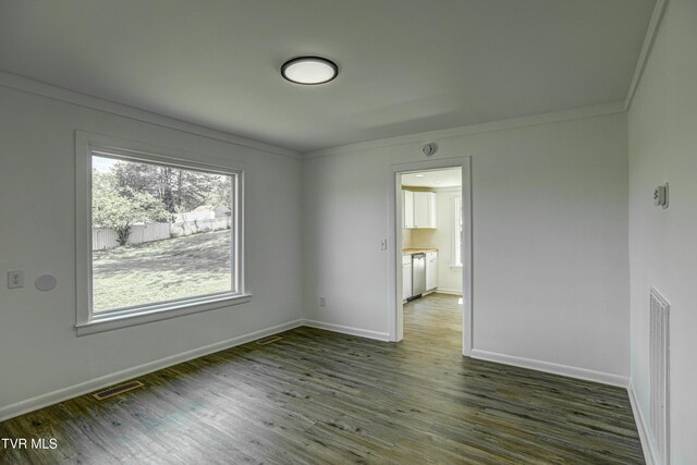 empty room featuring visible vents, ornamental molding, baseboards, and wood finished floors