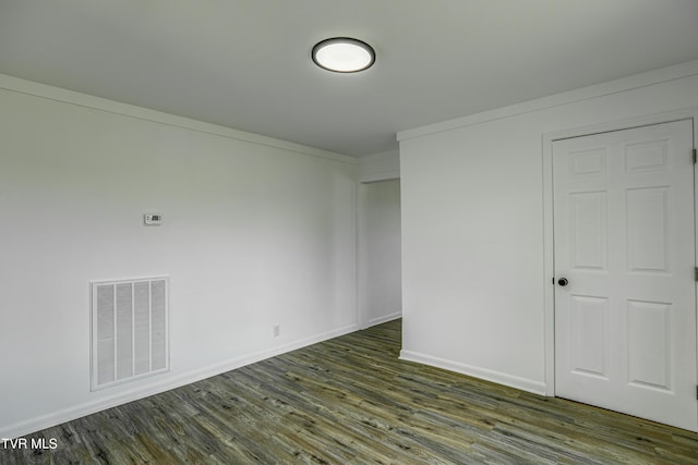 unfurnished room featuring visible vents, dark wood-style flooring, crown molding, and baseboards