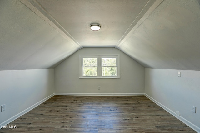 additional living space with a textured ceiling, baseboards, vaulted ceiling, and wood finished floors