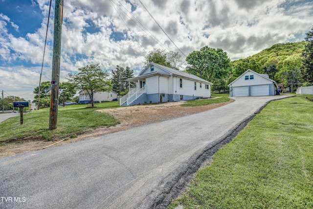 view of front of property featuring a detached garage, an outbuilding, and a front lawn