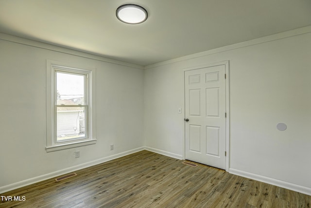 spare room featuring visible vents, baseboards, and wood finished floors