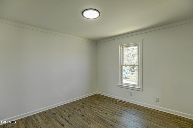 spare room with baseboards, visible vents, and wood finished floors