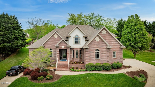 view of front of home with stucco siding, roof with shingles, a front lawn, and brick siding