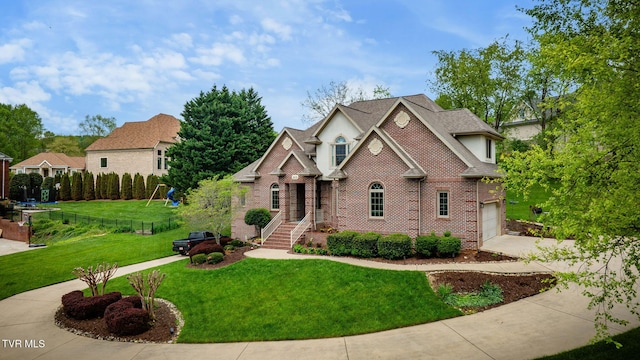 view of front of property with a front lawn, driveway, brick siding, an attached garage, and fence