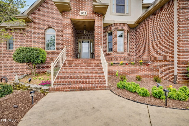 view of exterior entry with brick siding and stucco siding