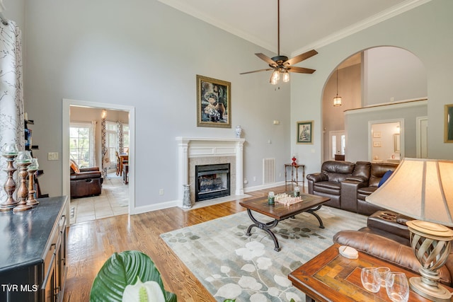 living area featuring a towering ceiling, visible vents, light wood-style flooring, and arched walkways