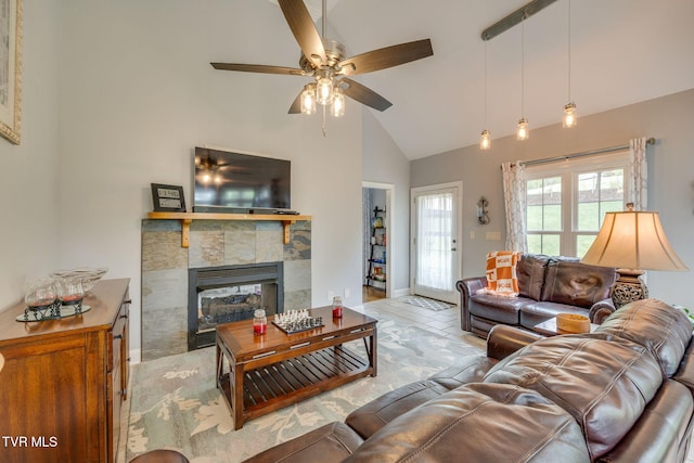 living area with baseboards, high vaulted ceiling, a ceiling fan, and a glass covered fireplace