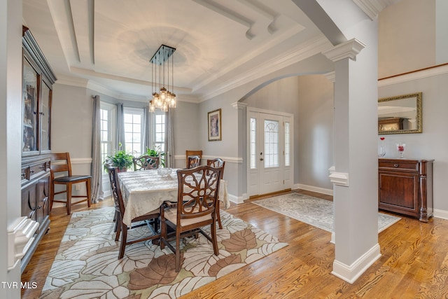 dining area featuring a wealth of natural light, light wood-style flooring, arched walkways, and decorative columns
