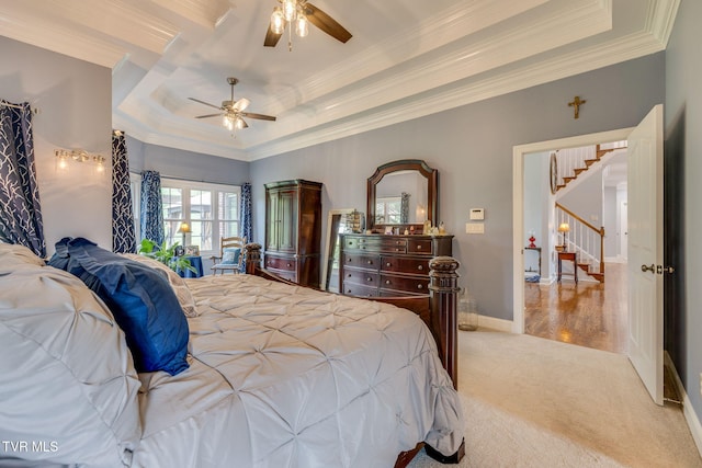 carpeted bedroom featuring crown molding, a ceiling fan, and a raised ceiling